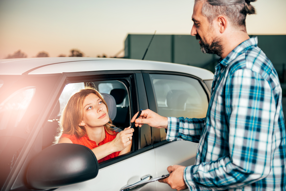 car-dealer-passing-a-pen-to-lady-in-a-company-car