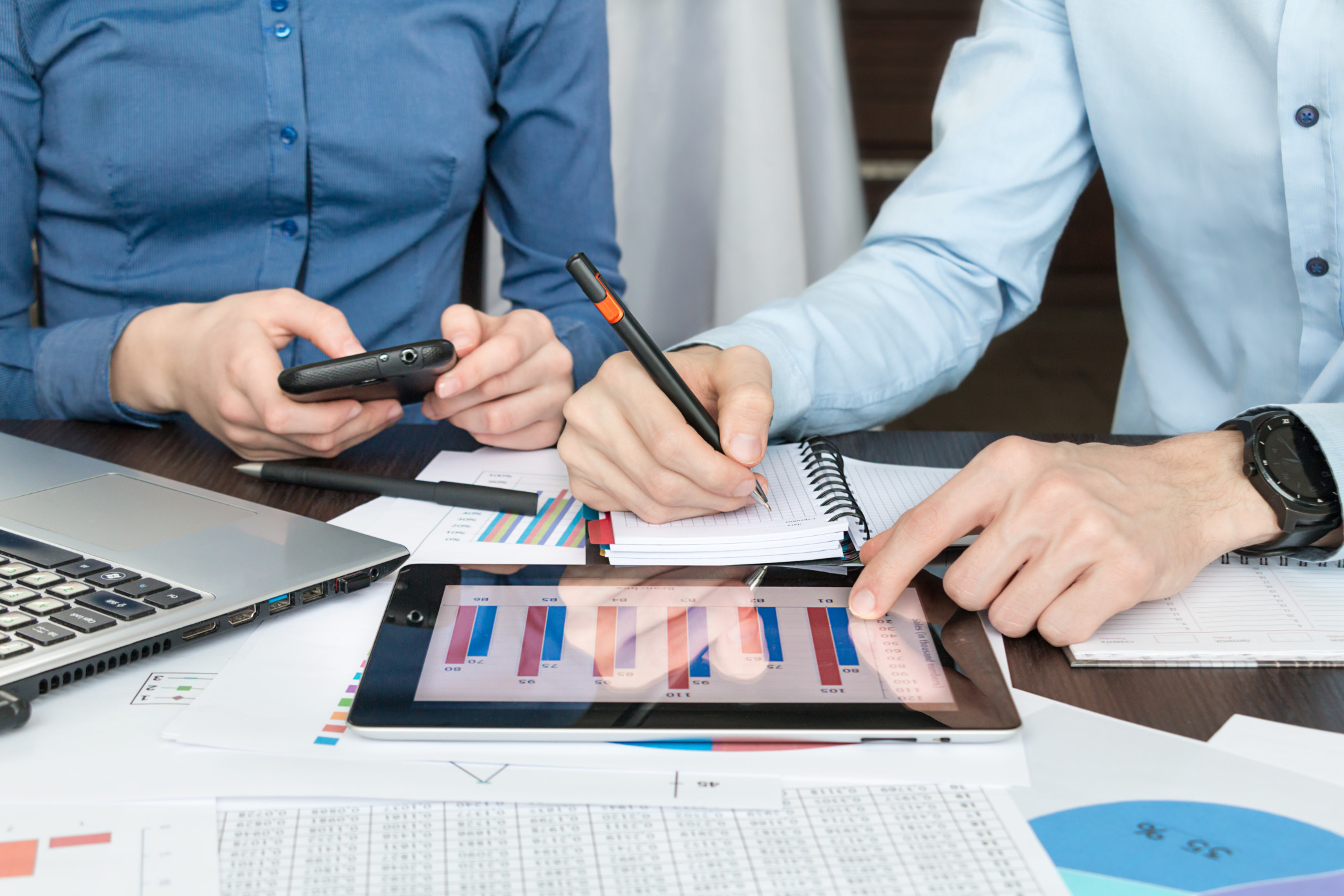 a-man-and-a-woman-sit-at-a-desk-in-the-office-and-do-business-analysis-using-a-phone-and-tablet